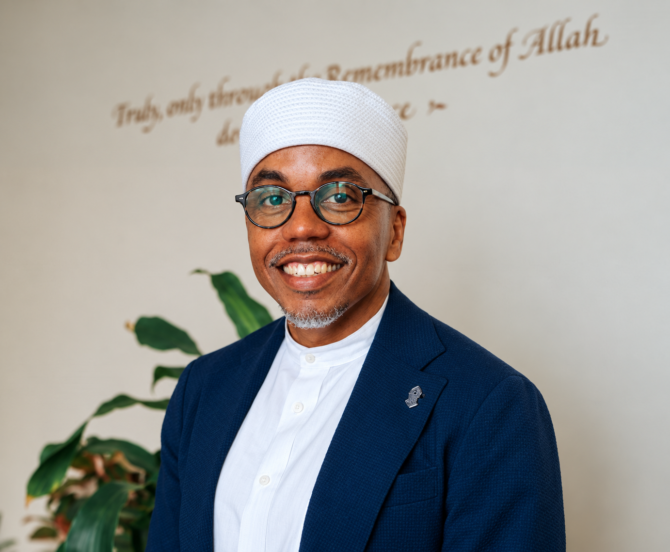 Khalis Rashaad smiling, wearing a navy blazer and white headwear